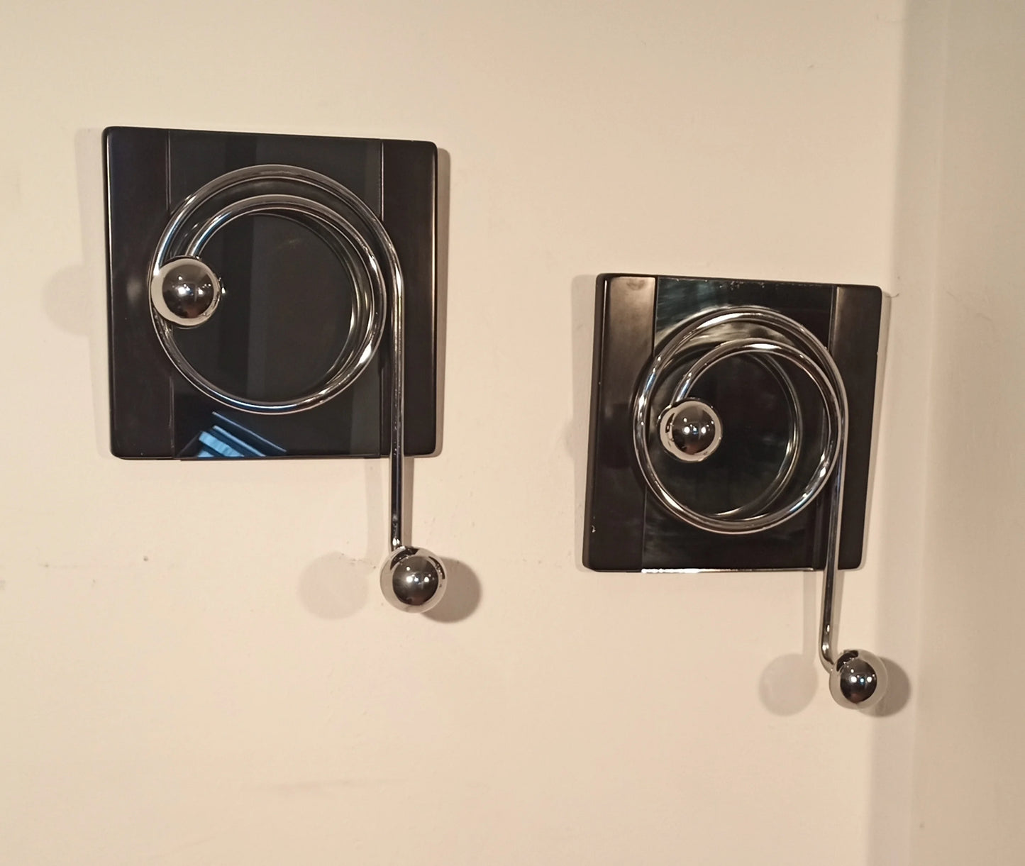 Two elegant wall coat hooks by Willy Rizzo with a spiral design in chrome on black plates from the 1970s.