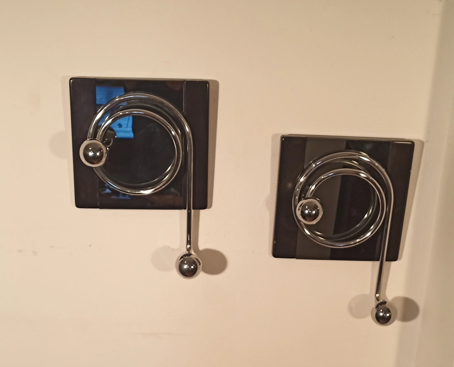 Two elegant Willy Rizzo wall coat hooks with a circular chrome design on a black plate from the 1970s.
