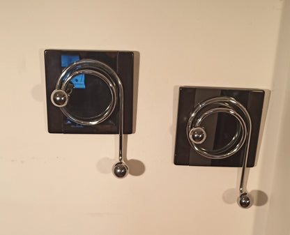 Two elegant Willy Rizzo wall coat hooks with a circular chrome design on a black plate from the 1970s.