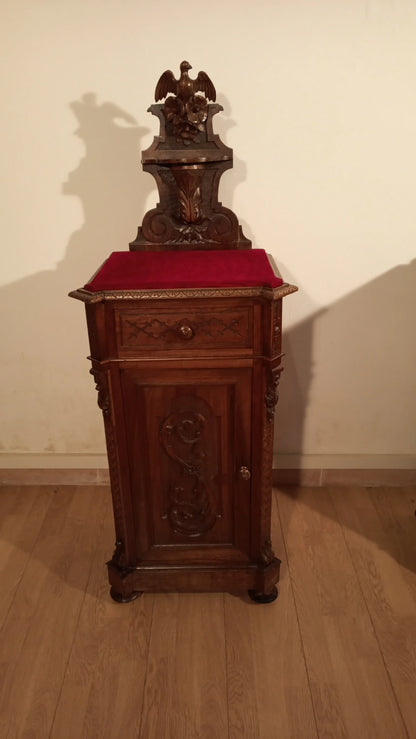 Small wooden clock on red cushion, part of a 19th century Italian walnut bedside table and chest of drawers set.