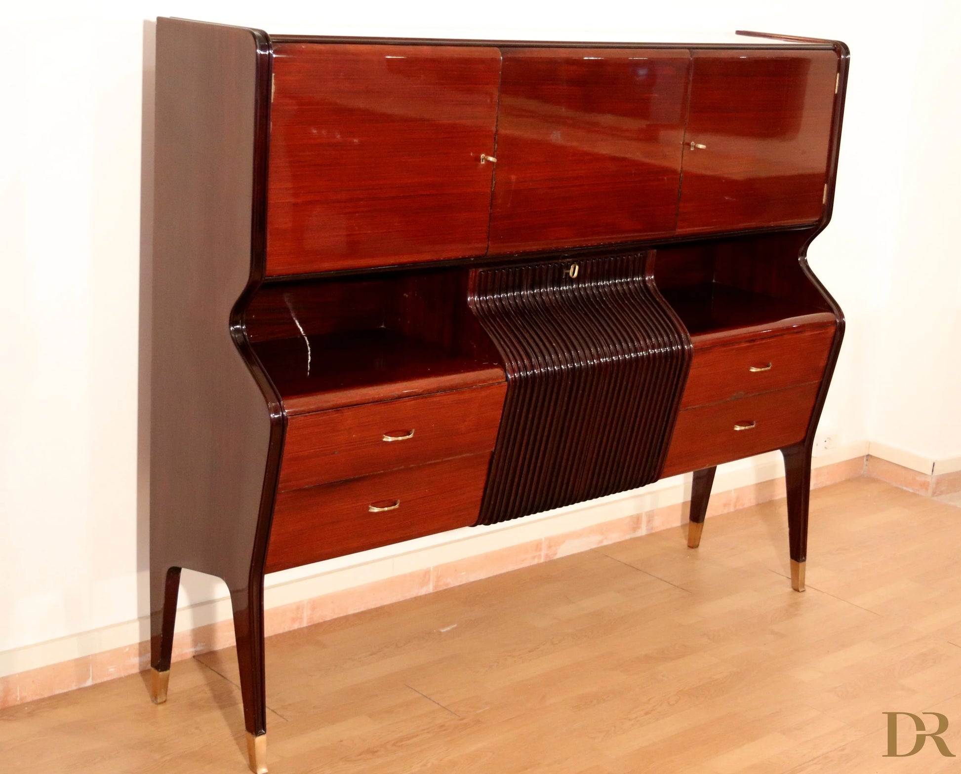 Mid-century mahogany sideboard by Osvaldo Borsani with curved top, slatted center panel, and slender brass legs.