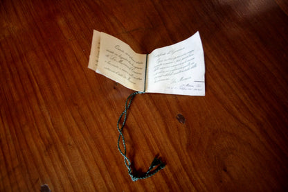 Open booklet with decorative string detailing a pendant chandelier by La Murrina, Italian design with signed brass