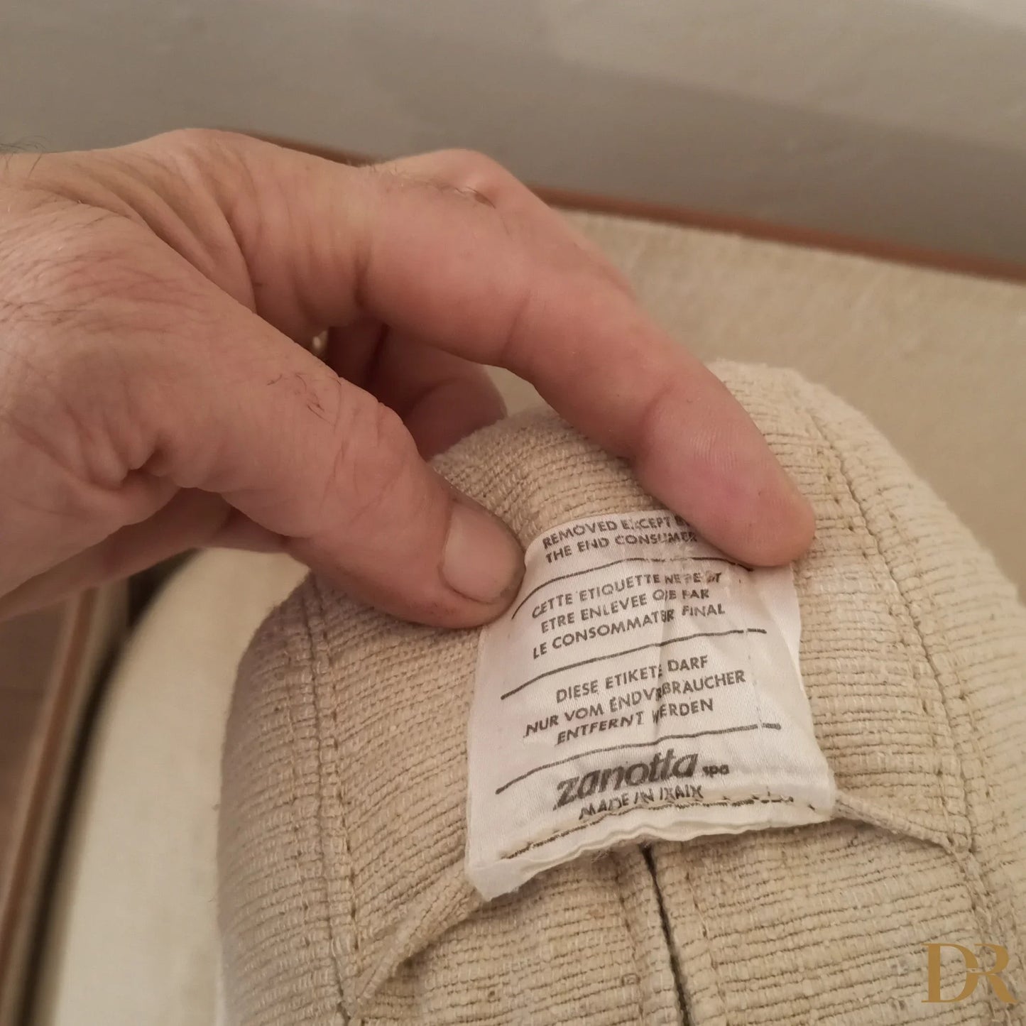 Mano che controlla l’etichetta di cura del divano modulare modello redifiori di riccardo arbizzoni per zanotta 1978