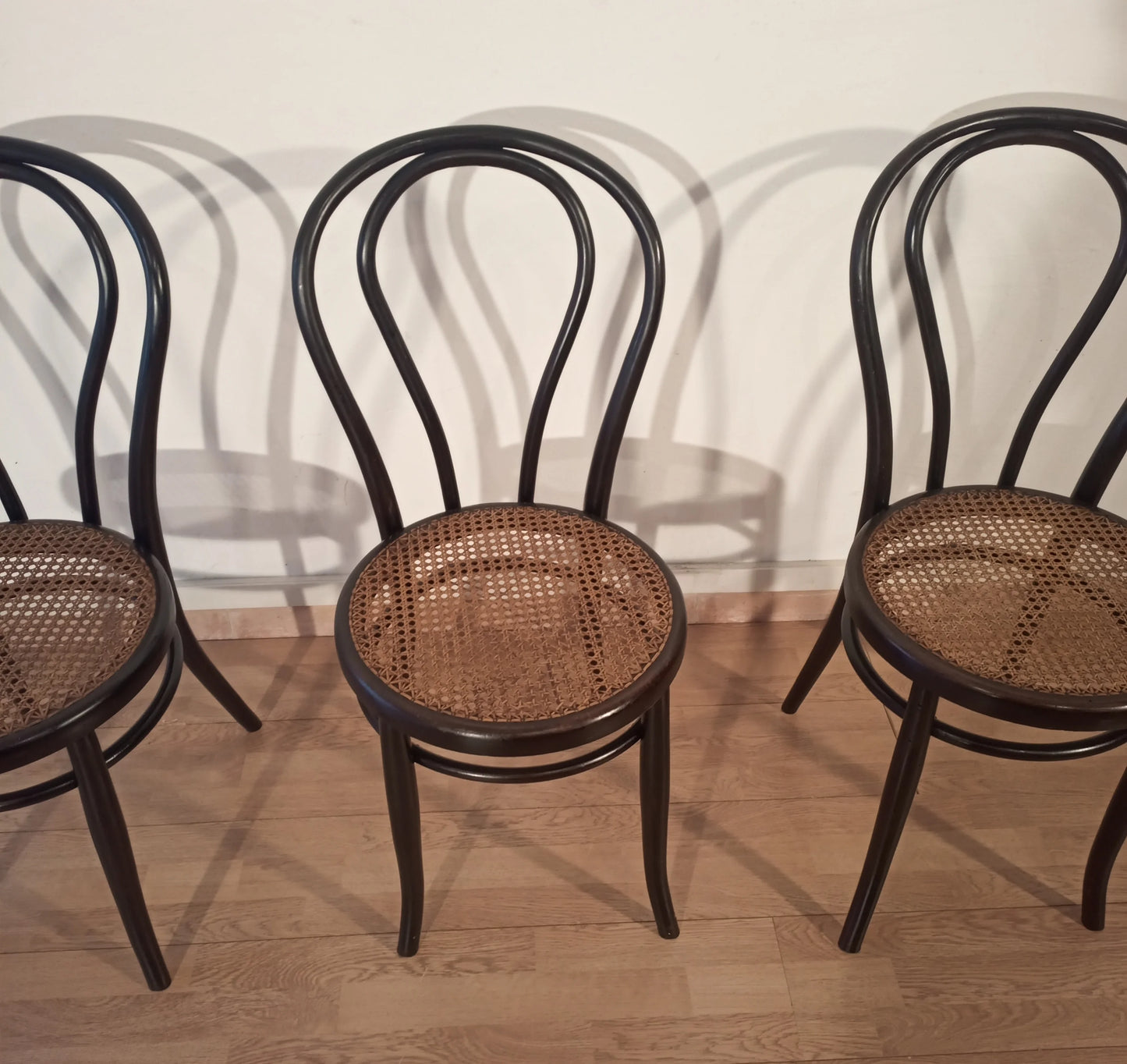 Three black bent beech chairs with wicker seats in the Thonet Italia set style, arranged in a row