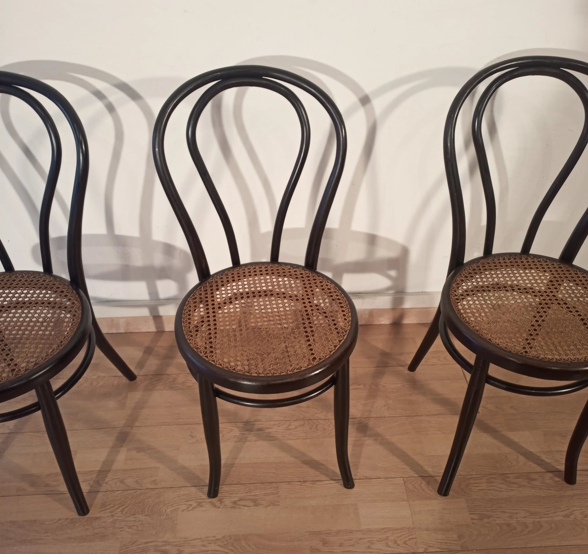 Three black bent beech chairs with wicker seats in the Thonet Italia set style, arranged in a row