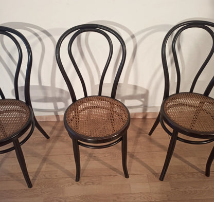 Three black bent beech chairs with wicker seats in the Thonet Italia set style, arranged in a row