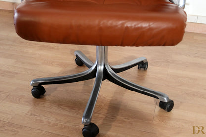 The Tecno P126 executive office chair in brown leather with a chrome base and black wheels designed by Osvaldo Borsani combines industrial aesthetics