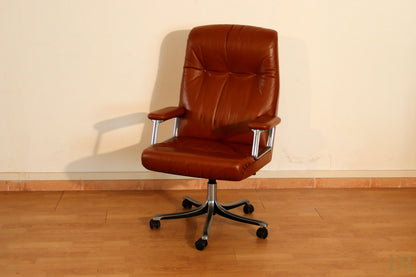 The Tecno P126 office chair in brown leather with chrome armrests combines the industrial aesthetic of Osvaldo Borsani.