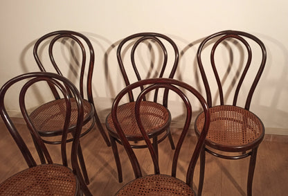 Set of five Thonet Drava style bentwood chairs with straw seats and curved light wood backrests.