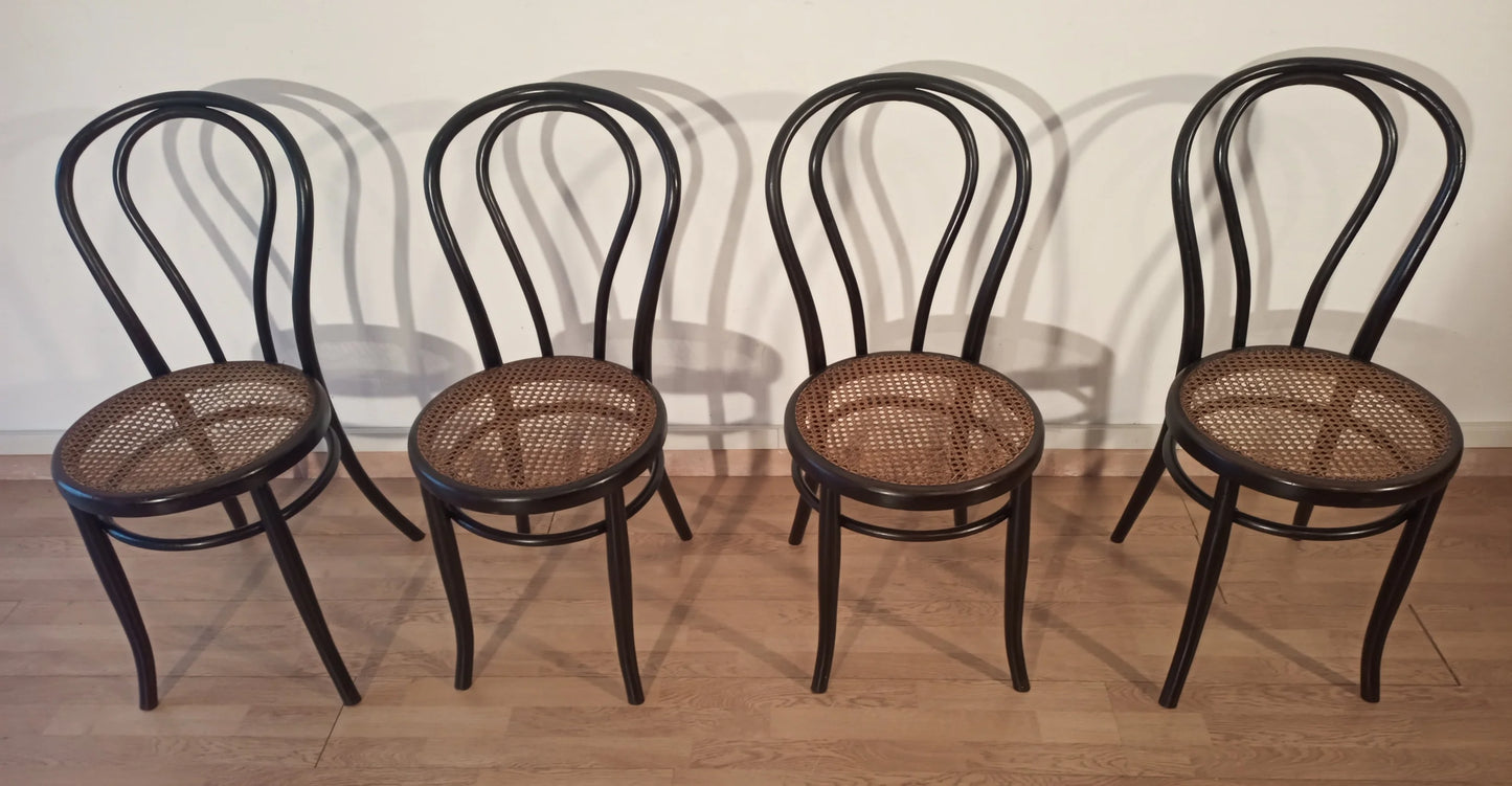 Four bent beech dining chairs with straw seats in the Thonet Italia style set arranged in a row