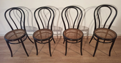 Four bent beech dining chairs with straw seats in the Thonet Italia style set arranged in a row